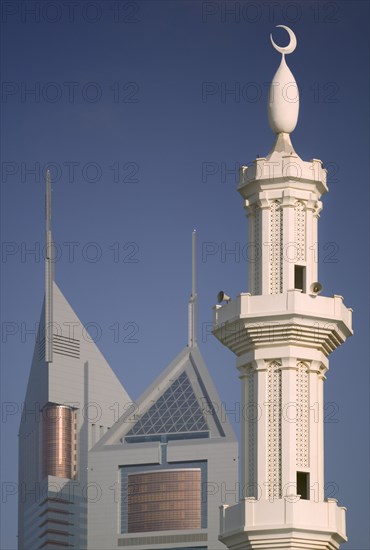 UAE, Dubai, The Emirates Towers with a minaret in the foreground.