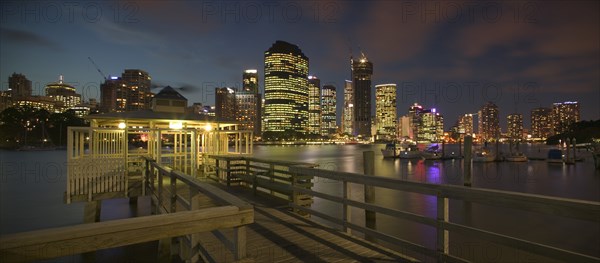 AUSTRALIA, Queensland, Brisbane, "View from a pier, of the CBD across the Brisbane River at dusk with boats on one side."