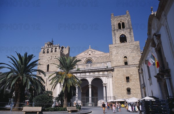 ITALY, Sicily, Palermo, Monreale. II Duomo Norman Cathedral exterior with people walking on road near small market stalls