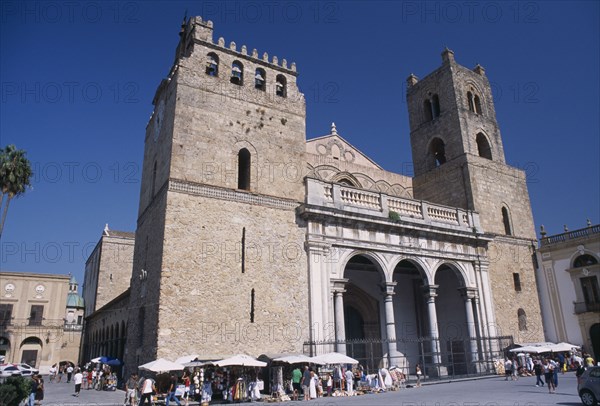 ITALY, Sicily, Palermo, Monreale. II Duomo Norman Cathedral exterior with people gathered around small market stalls next to the walls