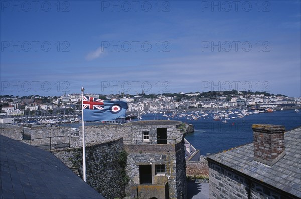UNITED KINGDOM, Channel Islands, Guernsey, St Peter Port. View from Castle Cornet with Union Jack flying. Marina and quayside buildings in the distance.