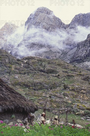 COLOMBIA, Santa Marta, Sierra Nevada , "Two Ica Indian brothers talking, with hut and mountains behind."