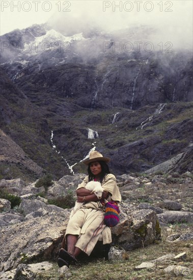 COLOMBIA, Santa Marta, Sierra Nevada , "Ica Indian with lamb sat on a rock, surrounded by mountains."