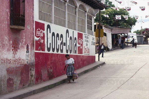 GUATEMALA, Solola, Indigenous woman walks down street past a Coca Cola street sign.