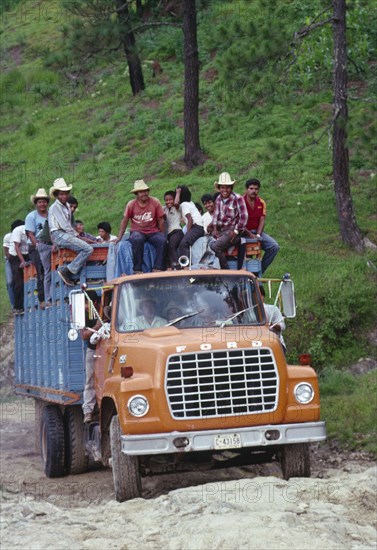 GUATEMALA, Highlands, Ford truck full of campesino men climbing a steep incline.