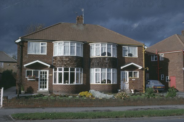 ENGLAND, Yorkshire, Leeds, Semi detached housing with a single car parked in the driveway.