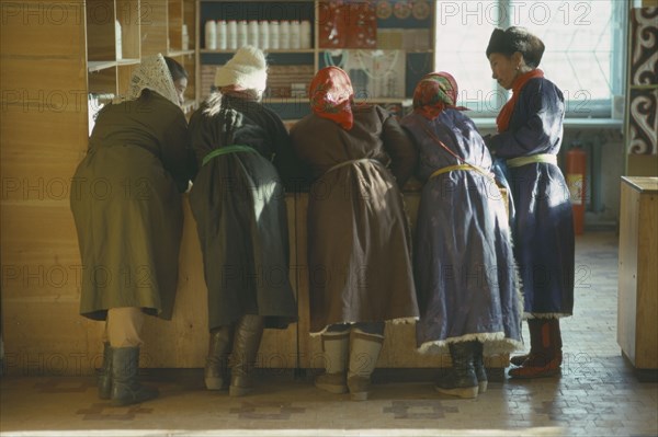 MONGOLIA, People, Group of women leaning on wooden shop counter to talk.