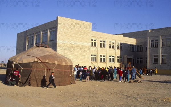 KAZAKHSTAN, Kyzlorda, "Yourt in Kazakh playground, with children and school behind."