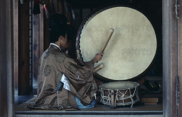 JAPAN, Honshu, Shimane, Izumo.  Priests striking large drum during worship at Izumo-Taisha one of the oldest Shinto shrines in the country dedicated to Okuninushi-no-Mikoto.