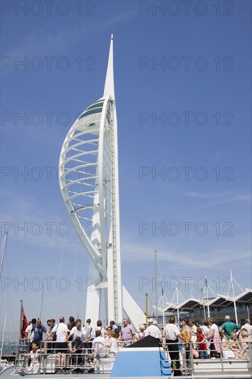 ENGLAND, Hampshire, Portsmouth, The Spinnaker Tower the tallest public viewing platforn in the UK at 170 metres on Gunwharf Quay with tourists on the deck of a harbour tour boat in the foreground