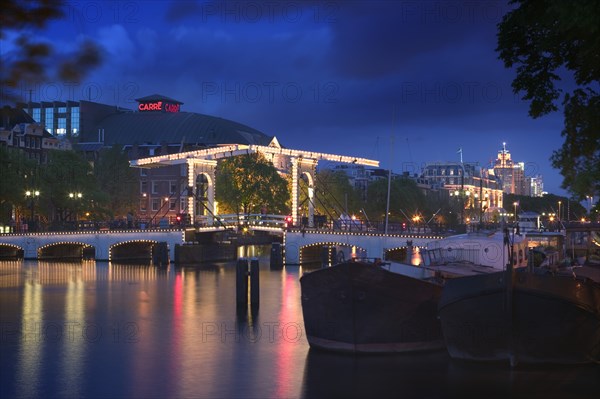 HOLLAND, North, Amsterdam, "Magere Brug, Skinny Bridge, at dusk with The Koninklijk Theater Carre behind."