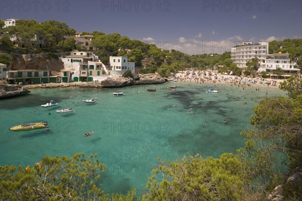 SPAIN, Balearic Islands, Mallorca, "Cala Santany, View of the beach with boats on the clear water."