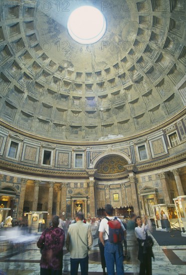 ITALY, Lazio, Rome, "Pantheon.  Interior of Roman temple, visitors looking up at circular opening or oculus in domed ceiling leeing in beam of light."