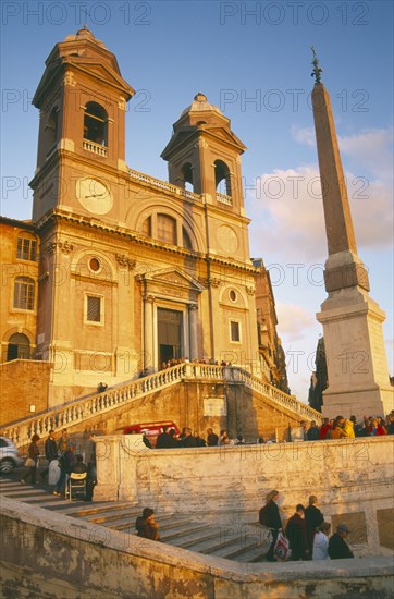 ITALY, Lazio, Rome, Trinita dei Monti sixteenth century church at the top of the Spanish Steps at sunset with tourist crowds.