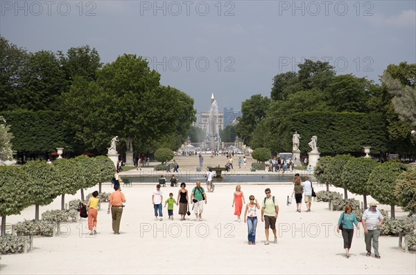 FRANCE, Ile de France, Paris, Tourists in the Jardin des Tuileries with the Obelisk and the Arc de Triomphe in the distance beyond the fountain