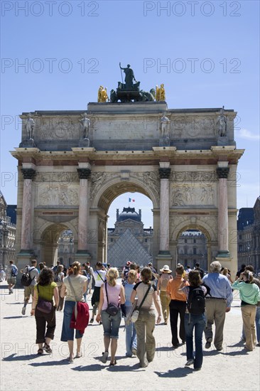 FRANCE, Ile de France, Paris, Tourists walking from the Jardin des Tuileries towards the Arc de Triomphe du Carrousel and the Musee du Louvre beyond