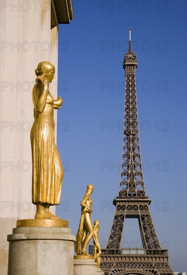 FRANCE, Ile de France, Paris, Gilded bronze statues in the central square of the Palais de Chaillot with the Eiffel Tower beyond