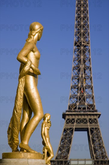 FRANCE, Ile de France, Paris, Gilded bronze statues in the central square of the Palais de Chaillot with the Eiffel Tower beyond