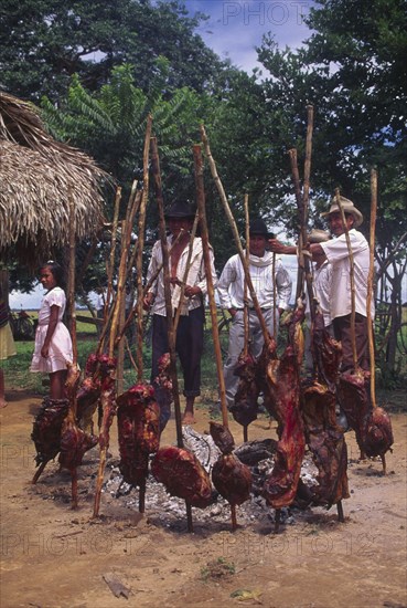 COLOMBIA, Casanare, "Carne a la llanera, A circle of meat on sticks round a fire with a few people standing next to it."