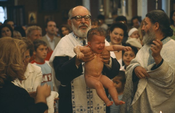 GREECE, Cyclades Islands, Syros, "A Greek orthodox christening, the child being held up by the Priest with friends and family behind."
