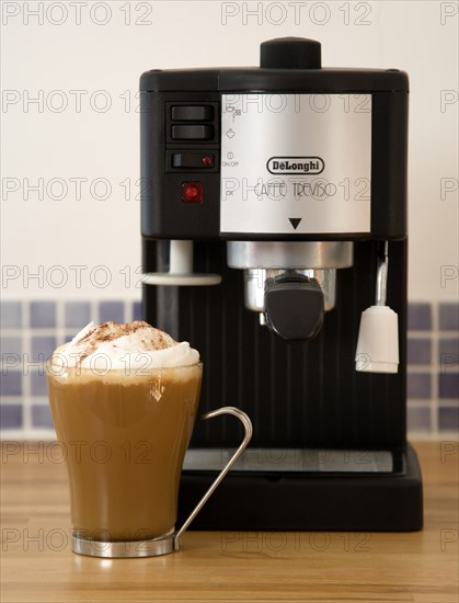 FOOD & DRINK, Coffee, Domestic Coffee machine on wooden kitchen worktop with a cup of cappuccino in a glass mug