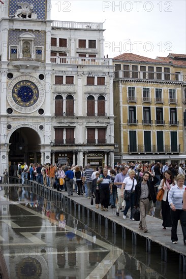 ITALY, Veneto, Venice, Aqua Alta High Water flooding in St Marks Square with tourists walking on elevated walkways beneath the Torre dell'Orologio clock tower Paul Seheult