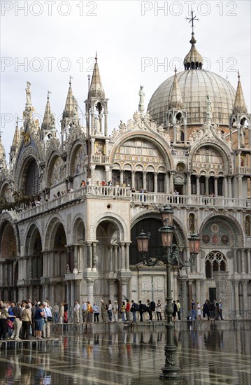 ITALY, Veneto, Venice, Aqua Alta High Water flooding in St Marks Square with tourists walking on elevated walkways above the water beside St Marks Basilica Paul Seheult