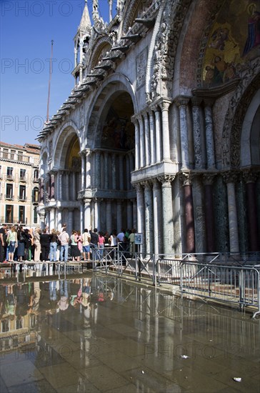 ITALY, Veneto, Venice, Aqua Alta High Water flooding in St Marks Square with tourists queuing on elevated walkways to enter St Marks Basilica