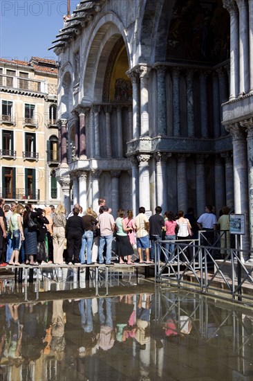 ITALY, Veneto, Venice, Aqua Alta High Water flooding in St Marks Square with tourists queuing on elevated walkways to enter St Marks Basilica Paul Seheult