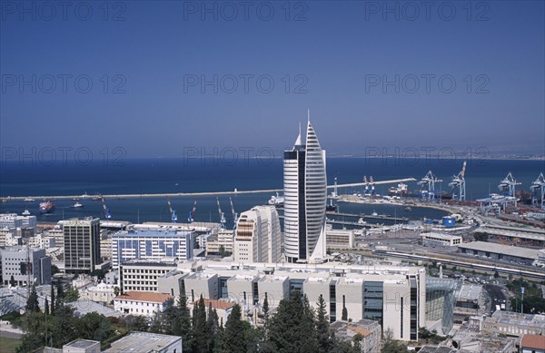 ISRAEL, Haifa, Elevated view of downtown area with modern tall buildings including a fish shaped skyscraper towards the docks and coastline in the background