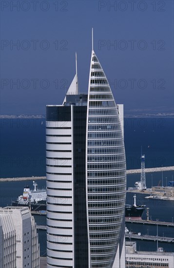 ISRAEL, Haifa, Tall modern fish shaped skyscraper with the docks and coastline seen in the background