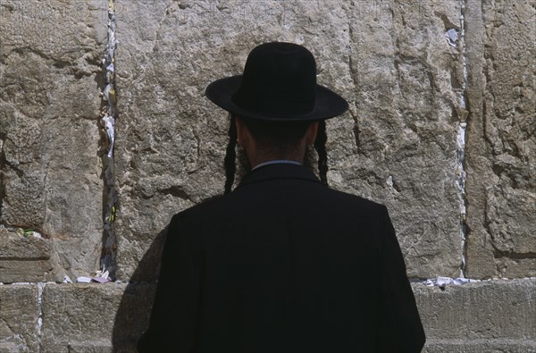 ISRAEL, Jerusalem, An Ultra Orthodox Jewish Man wearing a black hat and coat praying at the Western Wall
