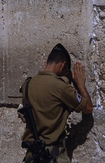 ISRAEL, Jerusalem, An Israeli Soldier in army uniform with an M16 Assault Riffle over his shoulder praying at The Western Wall