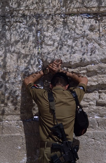 ISRAEL, Jerusalem, An Israeli Soldier in army uniform with a M16 Assault Riffle around his shoulder praying at The Western Wall