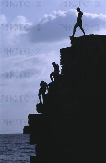 ISRAEL, Acre, Arab boys climbing the old harbour walls to jump into the sea