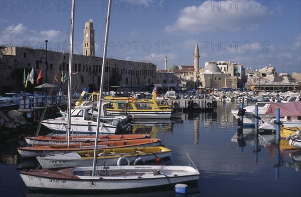 ISRAEL, Acre, "View across the harbour with moored boats towards Mosques, Minarets and an ancient fortress"