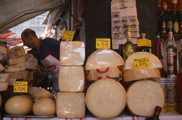 ITALY, Sicily, Catania, Market cheese stall with male stall holder displaying a selection of cheeses and euro money price signs