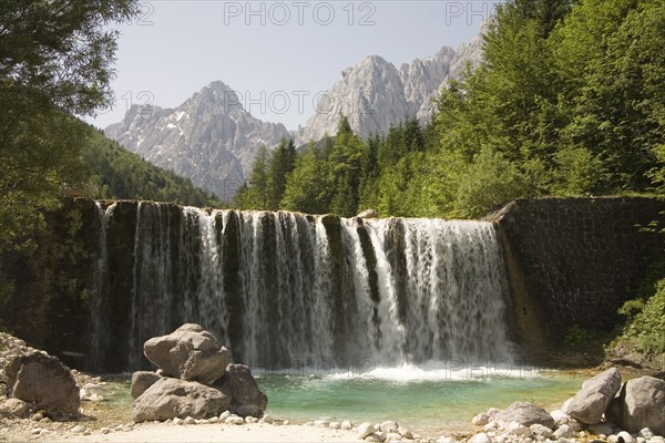 SLOVENIA , Kranjska Gora, Julian Alps, A waterfall on Velika Pisnica with Mounts Razor and Prisank in the Julian Alps in the background. There is still snow lying on the mountain after a severe winter