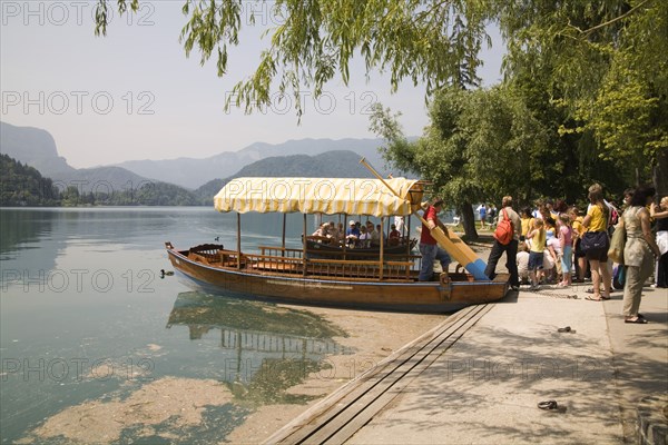 SLOVENIA, Lake Bled, Tourists queuing to board one of the rowing boats for a trip to the island and church - the second boat has just arrived back