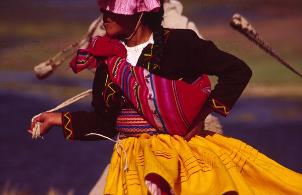 PERU, Puno Administrative Department, Lake Titicaca, "Aymara dancer dressed in her traditional costume, an Aymara girl performs a folk dance on the shore of Lake Titicaca"