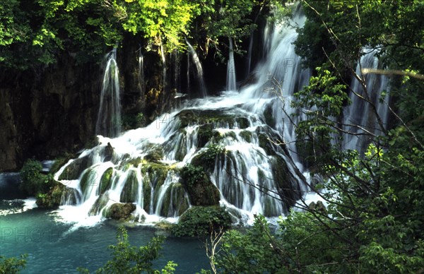 CROATIA, Lika, Plitvice, Plitvice lakes waterfall into lower lakes. Water follows the sinuous travertine (porous rock formation) line from the upper to lower lakes