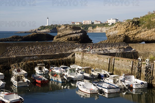 FRANCE, Aquitaine Pyrenees Atlantique, Biarritz, The Basque seaside resort on the Atlantic coast. Boats in the safe harbour of the Port des Pecheurs with the lighthouse in the distance.