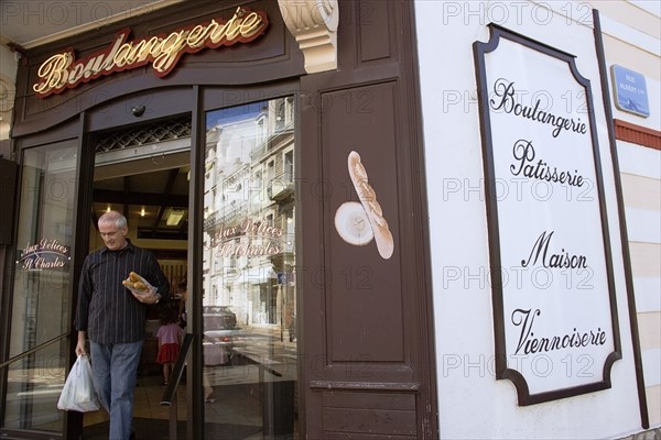 FRANCE, Aquitaine Pyrenees Atlantique, Biarritz, The Basque seaside resort on the Atlantic coast. Man leaving boulangerie bakery with baguettes under his arm in the commercial centre of the town.