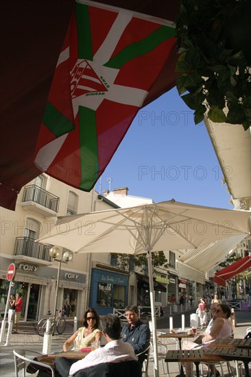 FRANCE, Aquitaine Pyrenees Atlantique, Biarritz, The Basque seaside resort on the Atlantic coast. The flag of Biarritz Rugby Football Club hanging up outside a bar with people sitting at tables under umbrellas