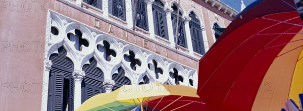 ITALY, Veneto, Venice, Facade of Danilei Hotel with coloured umbrellas on sale at street stall in the foreground.