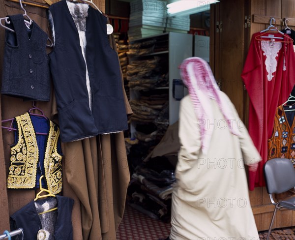 KUWAIT, Kuwait City, Man in Dishdasha and red and white shmaaq entering clothes shop in the Great Souq in blurred movement.