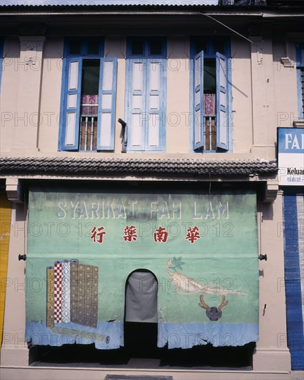 MALAYSIA, Kelantan, Kota Bharu, Jalan Temenggong.  Building exterior with painted shade hanging over entrance and open blue and white painted shutters above.