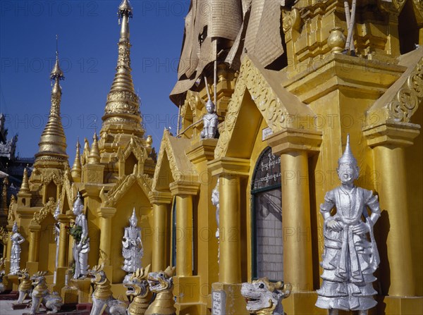 MYANMAR, Yangon, Shwedagon Paya.  Golden shrines and statues in temple complex.
