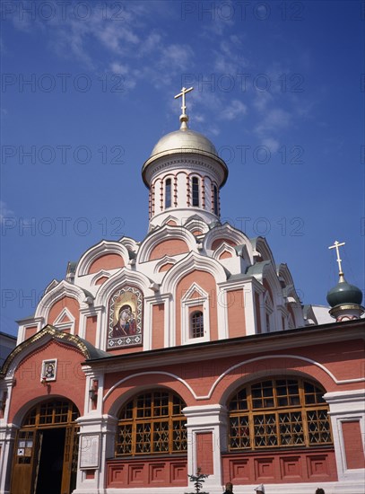 RUSSIA, Moscow, "Part view of exterior of refurbished church with red and white painted facade, gold domed roof and painted icons above the entrance."