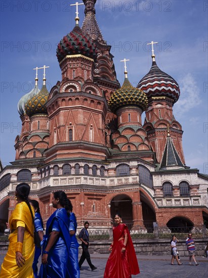 RUSSIA, Moscow, St Basil’s Cathedral exterior with women in brightly coloured saris in the foreground.
